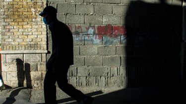 Una persona camina por una calle con una mascarilla.&nbsp;