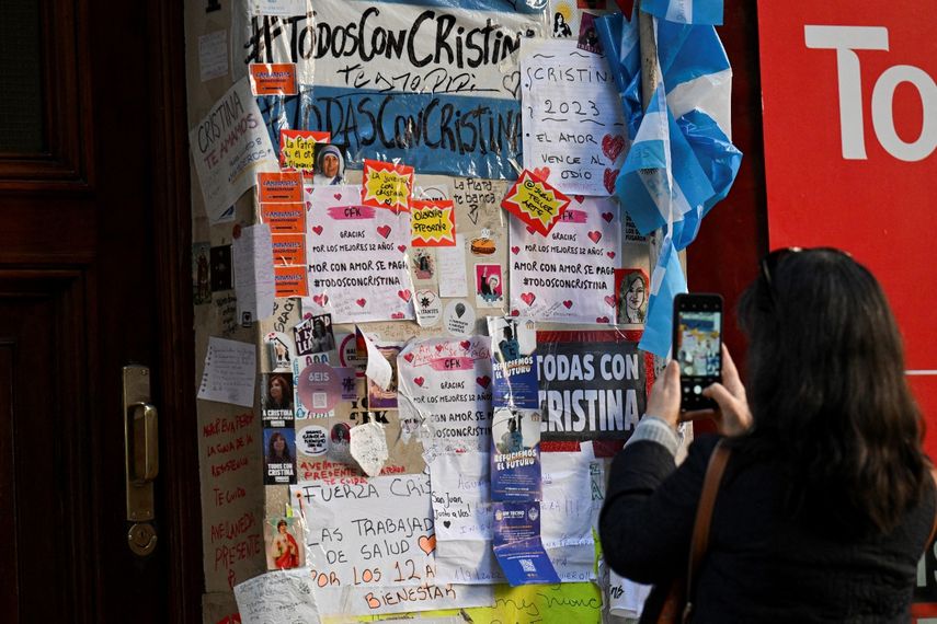 Una mujer toma fotografías de carteles dejados por simpatizantes de la vicepresidenta argentina Cristina Fernández de Kirchner afuera de su residencia en Buenos Aires, tras el atentado que sufrió.