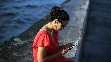 Una mujer accede a internet a través de su teléfono móvil en el malecón habanero.&nbsp;