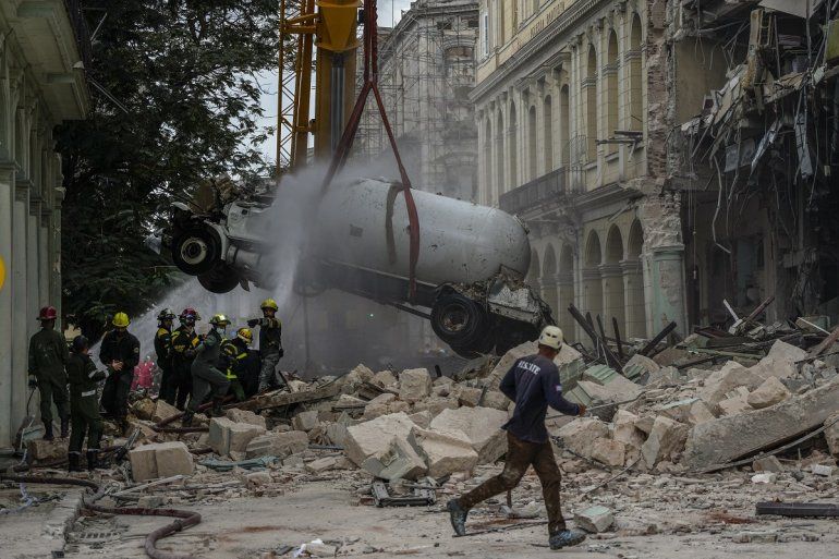 Los bomberos rocían con agua un camión cisterna para enfriarlo mientras lo retiran del lugar de una explosión letal que dañó el hotel Saratoga en La Habana, el viernes 6 de mayo de 2022. 