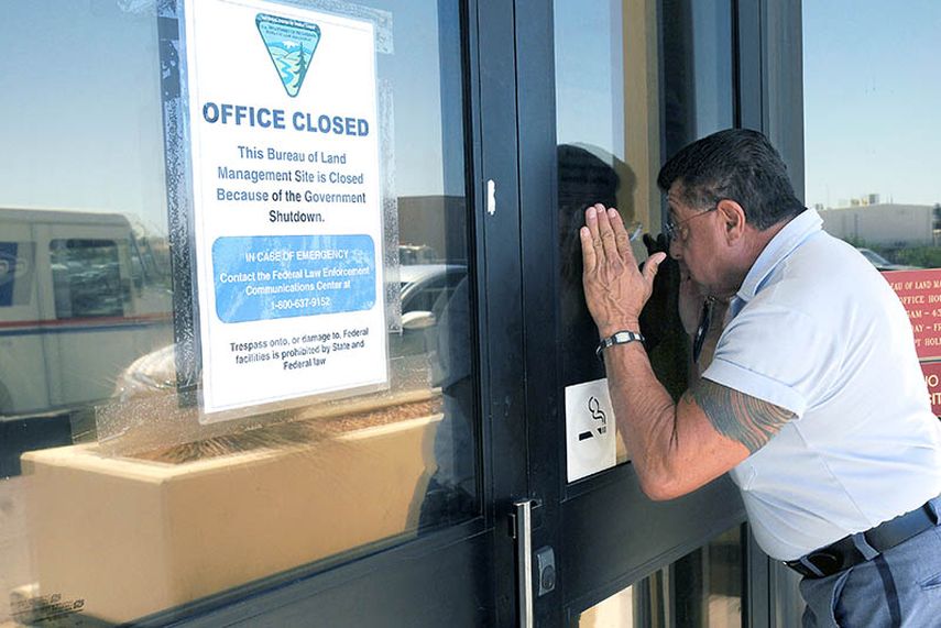 Un cartero mira a través de la puerta de una oficina gubernamental el martes en Las Cruces, Nuevo México. (AP)