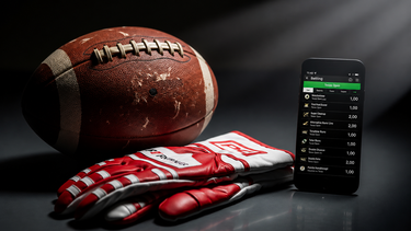 Un balón de football americano, guantes y una aplicación de apuestas deportivas ilustran el impacto creciente de las plataformas digitales en el negocio del deporte. &nbsp;