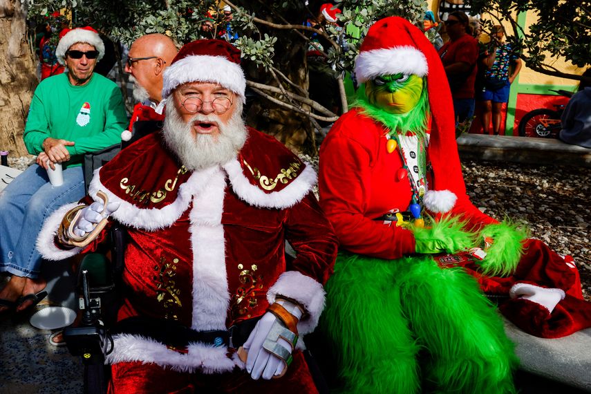 Personas vestidas como Papá Noel y el Grinch asisten al 15º evento anual “Surfing Santas” en Cocoa Beach, Florida, el 24 de diciembre de 2023. &nbsp;