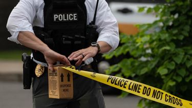 Un agente de la Policía acordona con cinta amarilla un área donde se realiza una investigación. 