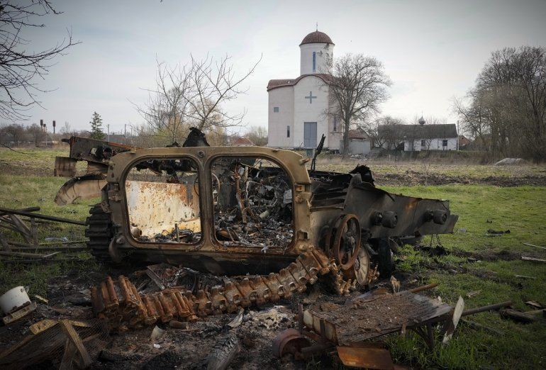 Fragmentos de un vehículo militar ruso se ven junto a una iglesia ortodoxa en el poblado de Lypivka, cerca de Kiev, Ucrania, el 11 de abril de 2022. 