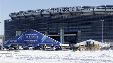 Un vehículo equipado con pala mecánica retira la nieve del estacionamiento del estadio MetLife Stadium cerca de uno de los accesos a la sede del Super Bowl XLVIII. (AP)