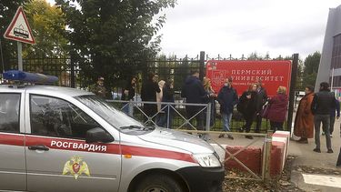 Gente tras una cerca cerca de la Universidad Estatal de Perm, con la Posguardia (Guardia Nacional) rusa a la izquierda, en Perm, Rusia, el lunes 20 de septiembre de 2021. Varias personas murieron tras un tiroteo en una universidad en la ciudad rusa de Perm, según el Comité Investigador ruso.