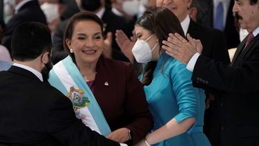La presidenta Xiomara Castro sonríe mientras recibe la banda presidencial, y su esposo, el expresidente Manuel Zelaya, aplaude.