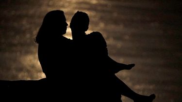 Silueta de una pareja que conversa bajo la luz de la luna en la ribera del r&iacute;o Missouri. Ambientes como este pueden ser propicios para hablar de las finanzas de una pareja, charlas que son vitales para la salud de la relaci&oacute;n, seg&uacute;n expertos.
