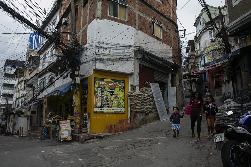 Unos residentes caminan frente a un edificio con orificios de bala días después de un operativo de la policía en la favela de Jacarezinho, en Río de Janeiro, Brasil, el sábado 8 de mayo de 2021. 