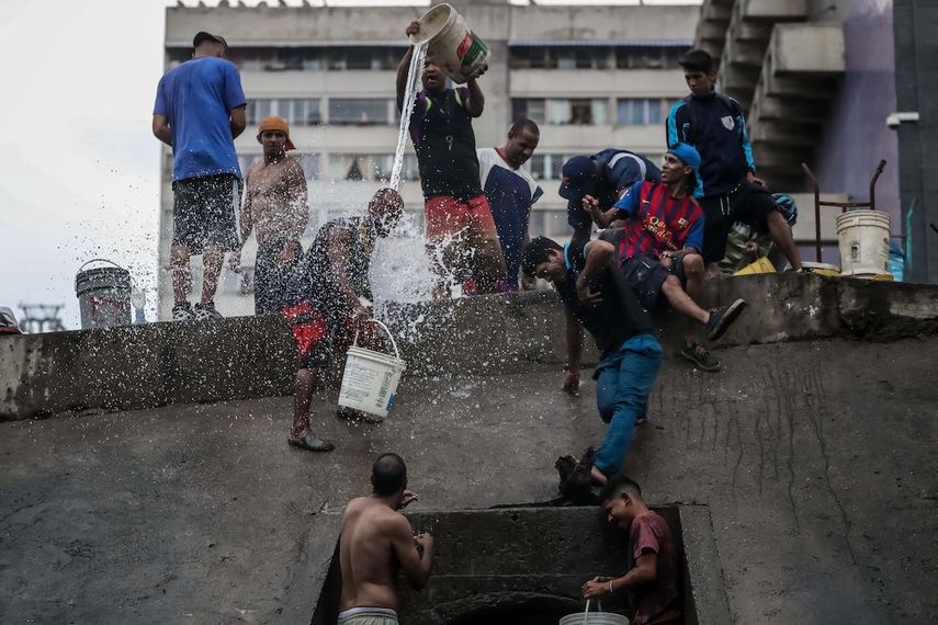 Caraqueños sacan agua de una toma que cae al río de aguas servidas que recorre la ciudad capital.