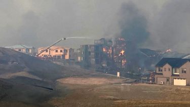 Los bomberos rocían agua en una estructura mientras crece un incendio forestal, el jueves 30 de diciembre de 2021, en Superior, Colorado. (AP Foto/David Zelio)