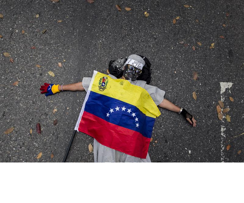Una mujer permanece en el suelo con una bandera venezolana, el pasado miércoles 25 de febrero de 2015, durante una manifestación convocada por un sector de la oposición venezolana frente a la Nunciatura apostólica, en Caracas, por la muerte de un adole