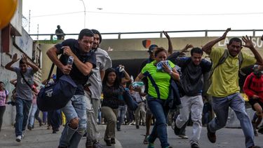 Un grupo de venezolanos huye de la represión de los agentes de seguridad del régimen de Nicolás Maduro durante una protesta opositora en Caracas.