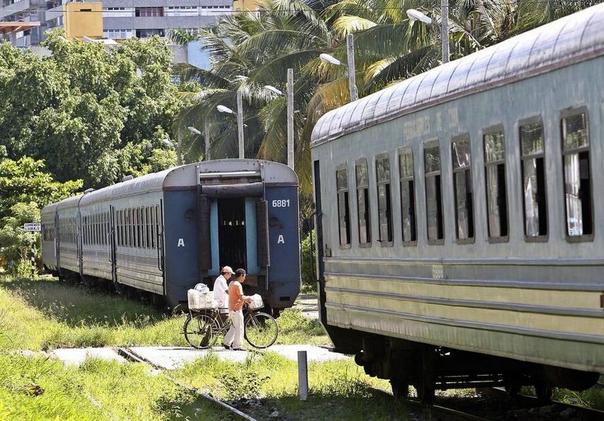 Fotografía de archivo fechada en agosto de 2018 de dos personas que caminan entre dos vagones de un tren de pasajeros en las inmediaciones de una estación de trenes en La Habana, Cuba.