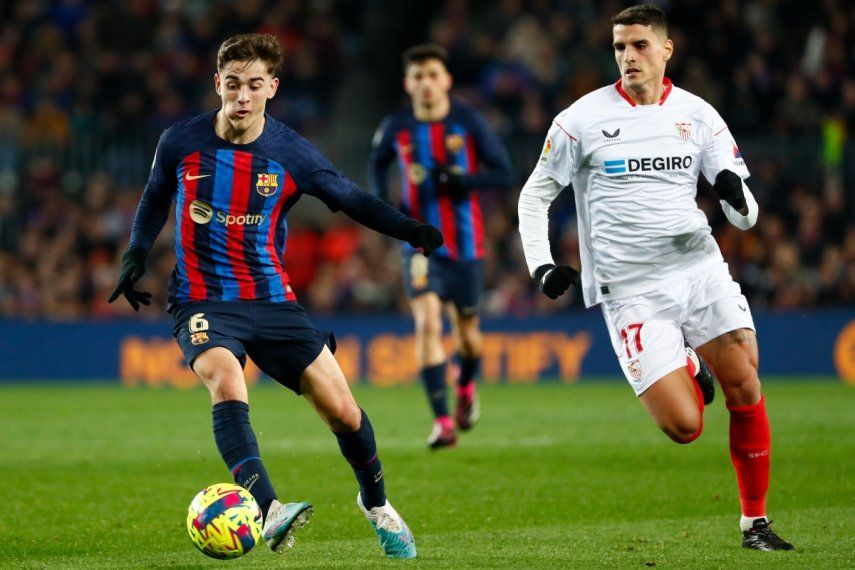 Gavi, izquierda, del Barcelona, avanza ante Erik Lamela, del Sevilla, durante un juego de la Liga española en el Camp Nou, el domingo 5 de febrero de 2023.