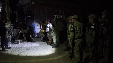 Efectivos de la nueva Guardia Nacional detienen a migrantes que viajaban de polizones en lo alto de los vagones del tren de carga conocido como La Bestia en la localidad de San Mateo, en el estado de Chiapas, México, la noche del miércoles 26 de junio de 2019. (AP Foto)