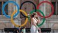 En foto del 25 de julio del 2022, una mujer pasa junto a los aros olímpicos afuera del ayuntamiento de París.