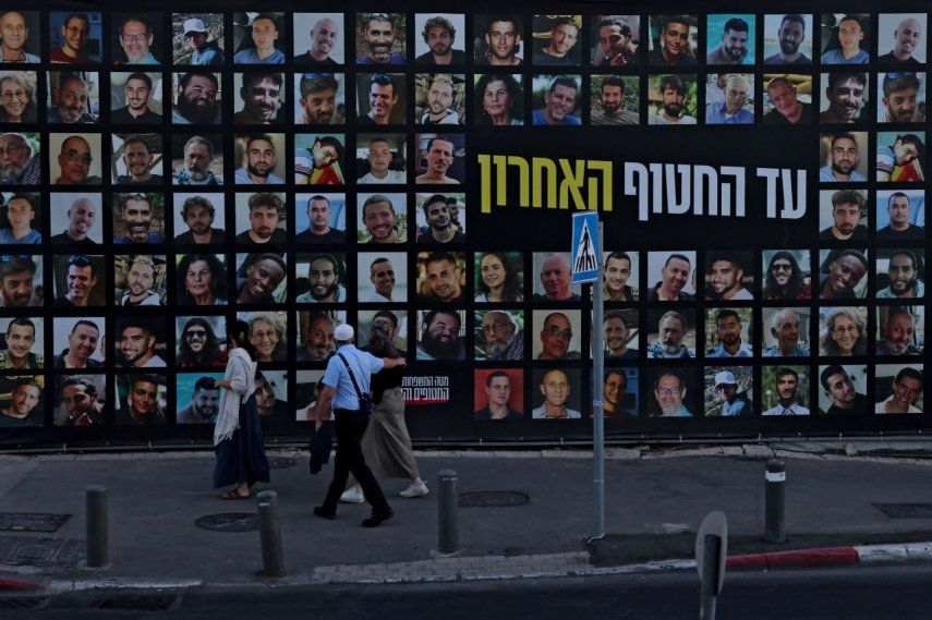 Personas observan una valla publicitaria que muestra los retratos de israelíes secuestrados por los terroristas de Hamás y que permanecen como rehenes en la Franja de Gaza desde octubre de 2023, en Jerusalén el 6 de octubre de 2025.