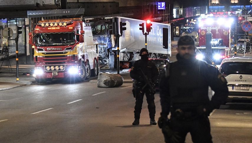 Dos policías vigilan durante el operativo para remover el camión con el que se perpetró el atentado de este vienes en Estocolmo, que causó la muerte de al menos cuatro personas.