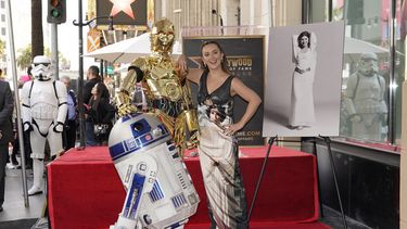 Billie Lourd, hija de la fallecida a actriz Carrie Fisher, posa con la estrella de Fisher en el Paseo de la Fama de Hollywood junto a los personajes de las películas de Star Wars C-3PO y R2-D2, durante una ceremonia póstuma en Los Ángeles el jueves 4 de mayo de 2023.