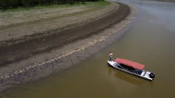 Un pescador de pie en su bote mientras navega cerca de miles de peces muertos en la orilla del lago Piraña debido a una sequía extrema en el estado de Amazonas, el miércoles 27 de septiembre de 2023, en Manacapuru, Brasil.