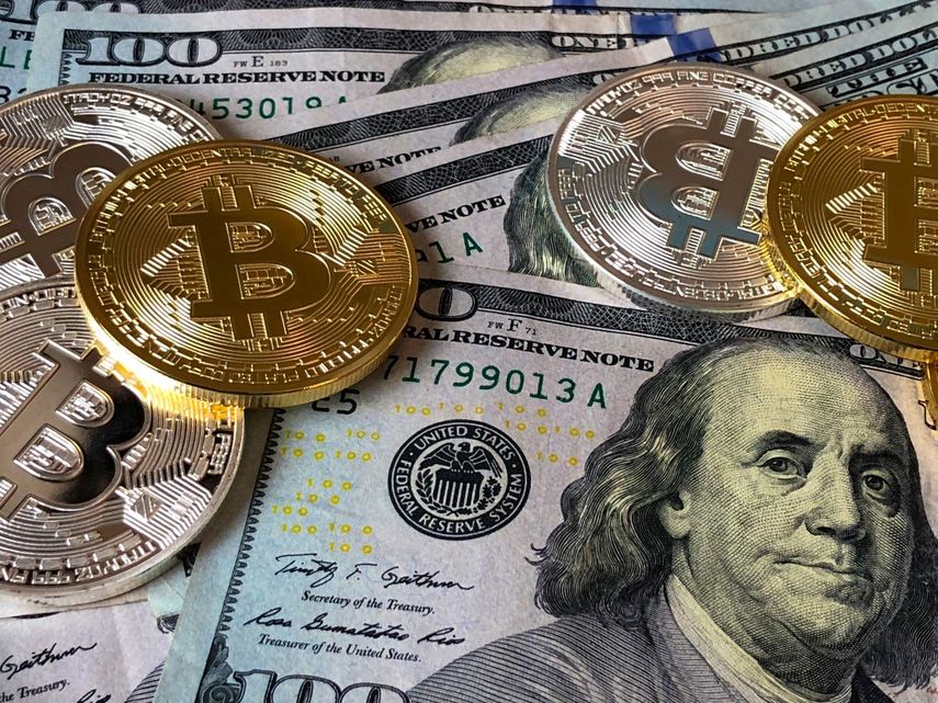 Billete de dólar junto a monedas de la criptomoneda bitcoin