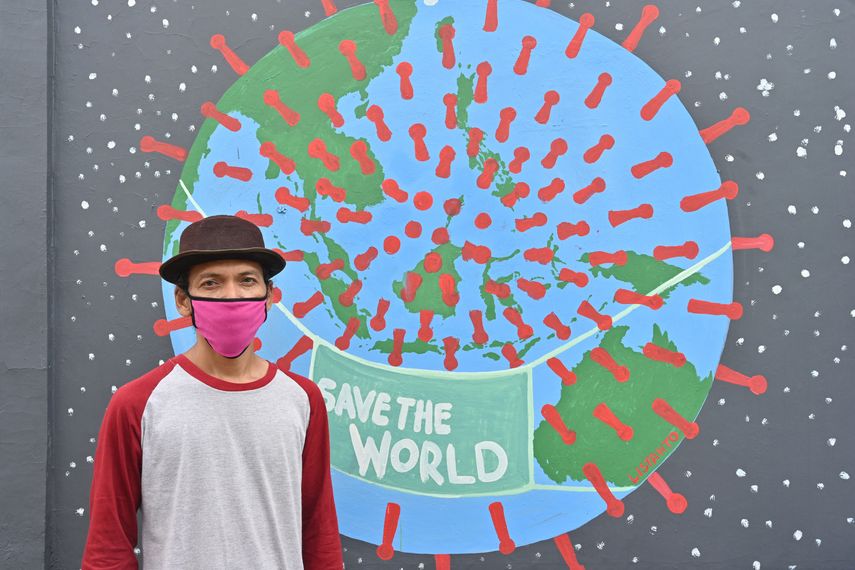 Esta fotograf&iacute;a tomada el nueve de abril de 2020 muestra al artista mural Sulis Listanto posando junto a su obra de arte en Indonesia, mientras los artistas locales se unen a la campa&ntilde;a en la lucha contra el brote de coronavirus.&nbsp;&nbsp;
