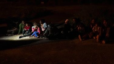 Varios migrantes, principalmente de Honduras y Nicaragua, hacen fila sentados después de entregarse al cruzar la frontera entre Estados Unidos y México, en esta fotografía de archivo del lunes 17 de mayo de 2021 en La Joya, Texas.&nbsp;