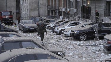 Un agente de policía camina por un estacionamiento con autos dañados, frente a un edificio de varias plantas, luego de un ataque ruso sobre Kiev, en Ucrania, el 30 de mayo de 2023.&nbsp;