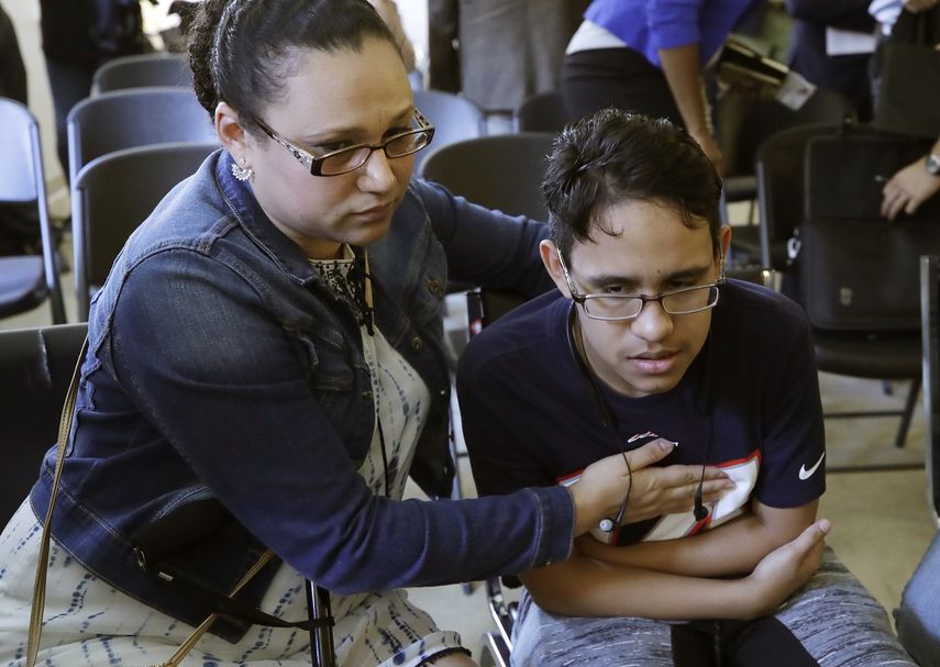 La hondureña Mariela Sánchez consuela a su hijo Jonathan, de 16 años, para quien buscan tratamiento médico en EEUU por su padecimiento de fibrosis quística, durante una conferencia de prensa el lunes 26 de agosto del 2019 en Boston.