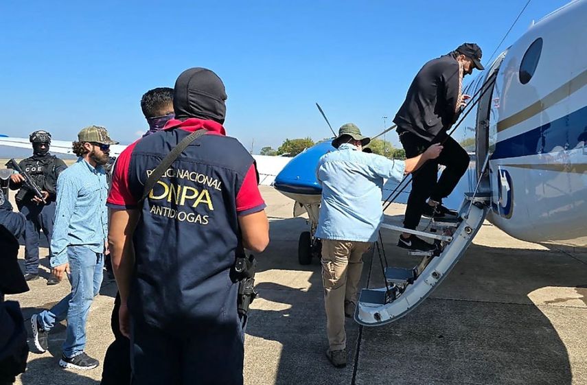 Un agente de la DEA custodia al presunto narcotraficante hondureño José Rafael Sosa, alias ‘Chafala’, mientras sube a un avión en la base aérea de Palmerola en la ciudad de Comayagua, a 50 km al norte de Tegucigalpa, el 4 de marzo de 2025.&nbsp;