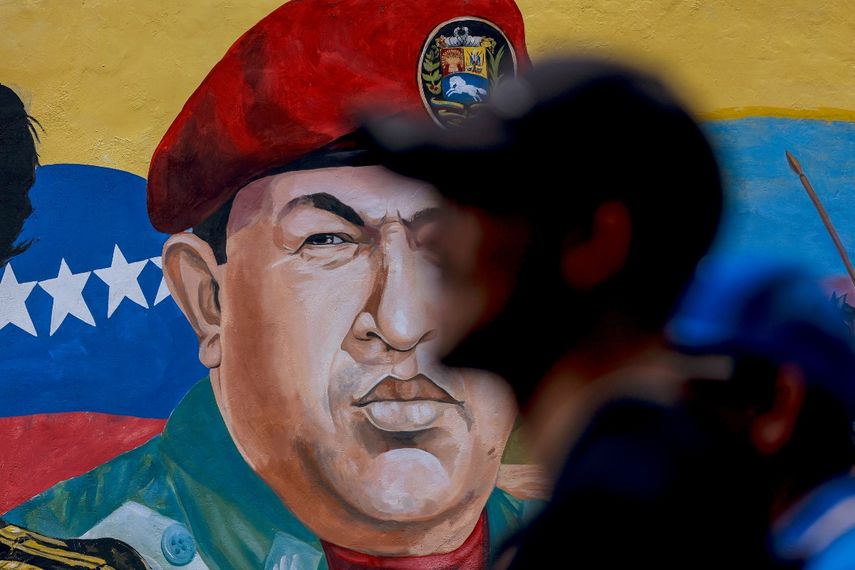 Un hombre pasa junto a un mural con la imagen del fallecido dictador de Venezuela, Hugo Chávez.
