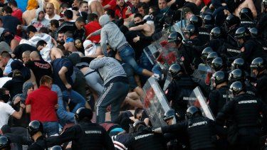 En esta foto del 16 de abril de 2016, policías antimotines chocan con hinchas del Estrella Roja durante un partido de la Liga Serbia ante el Partizan en Belgrado.