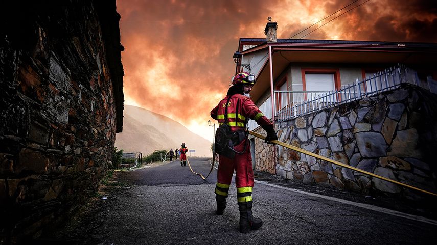 Bomberos tratan de apagar el fuego que se acerca a un pueblo en la provincia de León.
