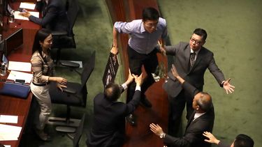 Agentes de seguridad persiguen al legislador prodemocracia Au Nok-hin, en el centro, mientras corre sobre la mesa para perseguir a la directora ejecutiva de Hong Kong, Carrie Lam, que abandona una sesi&oacute;n de preguntas con parlamentarios en el Consejo Legislativo de Hong Kong, el jueves 17 de octubre de 2019.&nbsp;