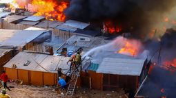 Vecinos ayudan a combatir un incendio en el barrio de escasos recursos de Laguna Verde, en Iquique, Chile, el lunes 10 de enero de 2022