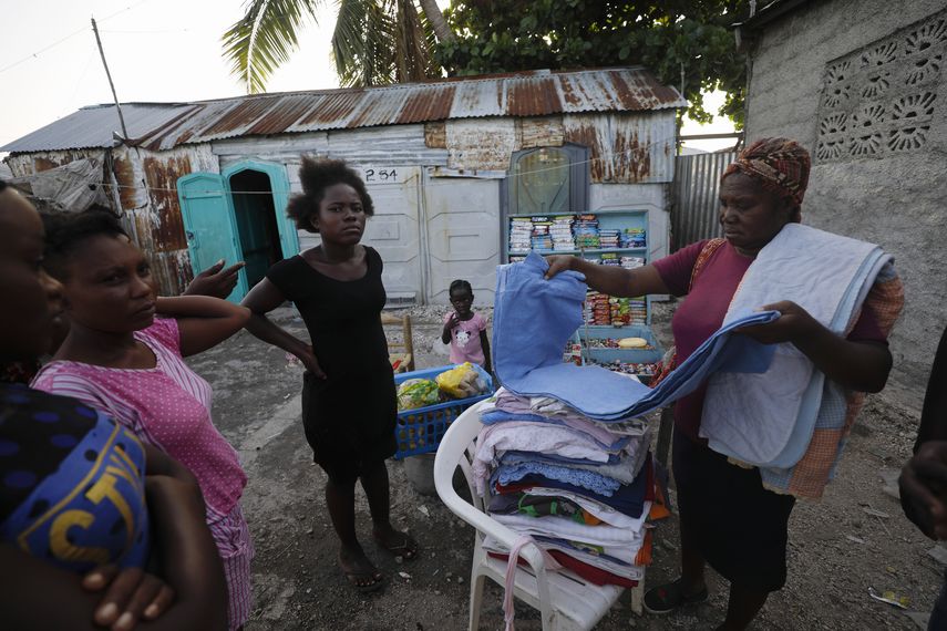 Una vendedora muestra su mercancía a posibles clientes frente a una vivienda semiconstruida en el barrio Cite Soleil, en Puerto Príncipe, Haiti, el jueves 10 de octubre de 2019. 