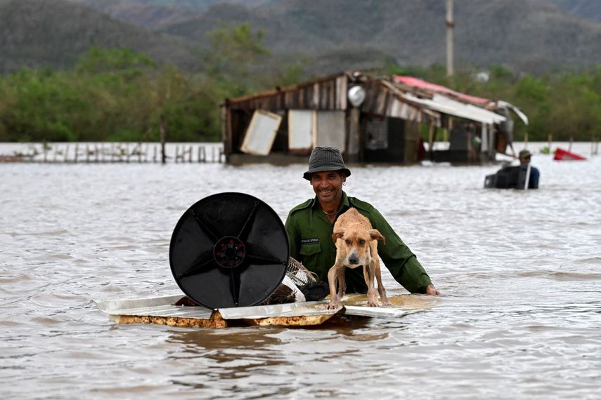 Un agricultor rescata a su perro y algunas pertenencias de su casa inundada después de que el huracán Melissa pasó por la localidad de San Miguel de Parada en la provincia de Santiago de Cuba el 29 de octubre de 2025.