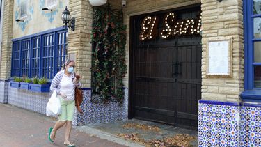 Una mujer camina por Calle 8, en Miami, protegida por una mascarilla.