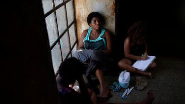 Una mujer se sienta frente a una ventana mientras acompaña a su hija en un edificio en el que viven en Río de Janeiro, el jueves 11 de marzo de 2021.