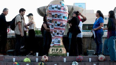 Personas y estudiantes de la Universidad Jesuita de Guadalajara (ITESO) colocan fotos de personas desaparecidas en una réplica del trofeo de la Copa Mundial de la FIFA, durante una intervención artística con el colectivo Luz y Esperanza en Guadalajara, Jalisco, México, el 21 de noviembre de 2025. México será uno de los tres países anfitriones de la Copa Mundial 2026, y Jalisco será sede de partidos clasificatorios.