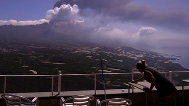 Un trabajador quita las cenizas de las mesas de un restaurantes mientras fluye la lava de un volcán en La Palma, Islas Canarias, España, 4 de octubre de 2021.&nbsp;