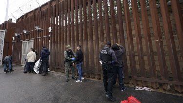 Oficiales federales estadounidenses le quitan las esposas a hombres antes de liberarlos cerca de la muralla fronteriza en San Diego el 15 de marzo de 2023.