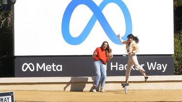 Empleados de Facebook se toman una foto con el nuevo nombre y log de la compañia afuera de su sede en menlo Park, California.&nbsp;