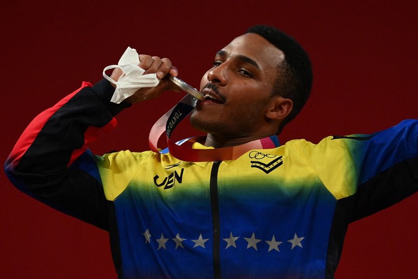 El venezolano Julio Rubén Mayora Pernia posa con su medalla de plata en el podio de la ceremonia de victoria de la competencia de halterofilia masculina de 73 kg durante los Juegos Olímpicos de Tokio 2020