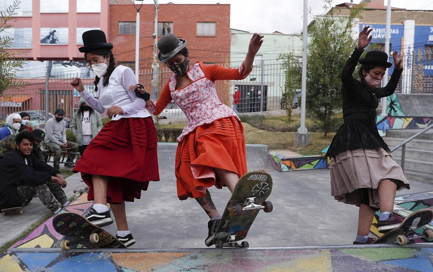 Milenda Limachi, izquierda, Yanira Villarreal, centro, y Ayde Choque, con m&aacute;scaras en medio de la pandemia de COVID-19 y vestidas como cholas en sus patinetas durante un show de talentos juveniles en La Paz, Bolivia.&nbsp;