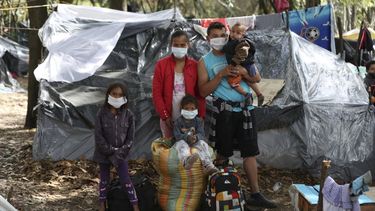 Liliana Hidalgo y Abrahan González posan con su hija (sentada) y dos sobrinas en el exterior de su tienda, en un parque donde viven junto a otros migrantes venezolanos desempleados desde finales de mayo, cerca de la estación de autobuses de Bogotá, Colombia, el 10 de junio de 2020.
