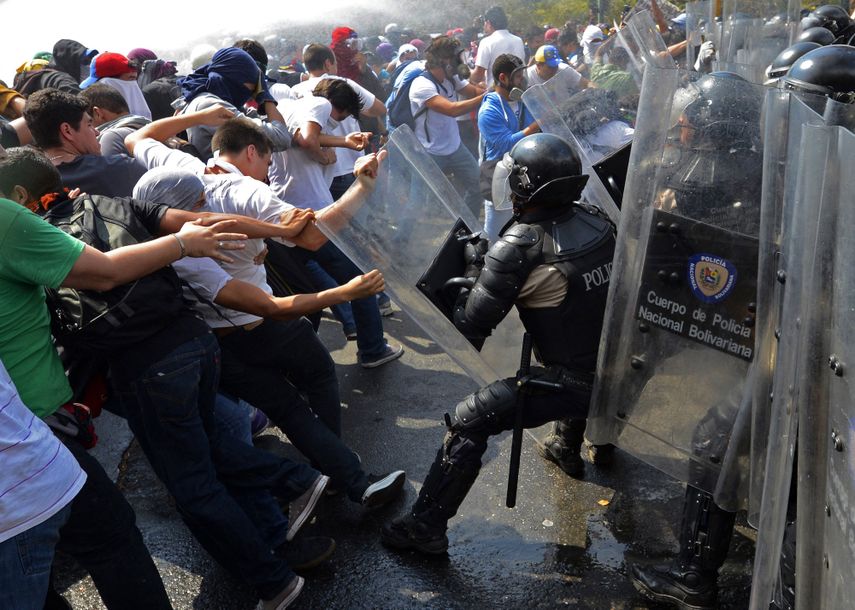 Estudiantes venezolanos se enfrentan a la policía antidisturbios durante una protesta contra el régimen del dictador venezolano Nicolás Maduro, en Caracas, el 12 de marzo de 2014. 