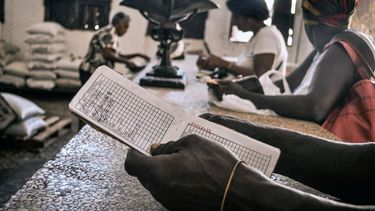 Unas personas esperan comida en una tienda, mientras una de ellas sostiene una libreta, una tarjeta de racionamiento que desde 1963 permite a los cubanos comprar alimentos básicos. 